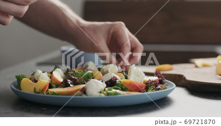 man making salad with nectarines and mozzarella on a blue plate on concrete countertop on kitchen, add mozzarella man making salad with nectarines and mozzarella on a blue plate on concrete countertop on kitchen, add mozzarella 69721870