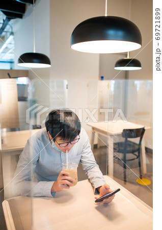 Drinking coffee in shield partition for social distancing 69721899