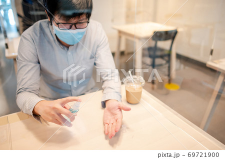 Cleaning hand with sanitizer spray in cafe Cleaning hand with sanitizer spray in cafe 69721900