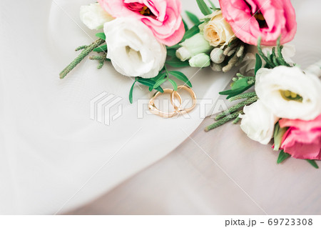 Beautiful toned picture with wedding rings against the background of a bouquet of flowers 69723308