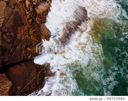 Aerial top view of sea waves hitting rocks on the cliffs Aerial top view of sea waves hitting rocks on the cliffs 69723684