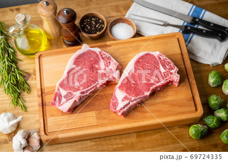 raw steak meat on cutting board in bright kitchen raw steak meat on cutting board in bright kitchen 69724335