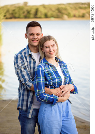Young couple walks and enjoys the evening sun near the rive. Young couple walks and enjoys the evening sun near the rive. 69724506