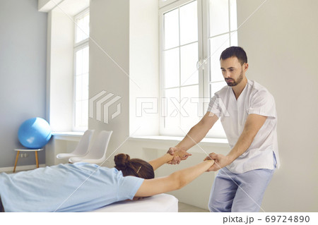 Male chiropractor or manual therapist curing client's spine problem in modern health center 69724890