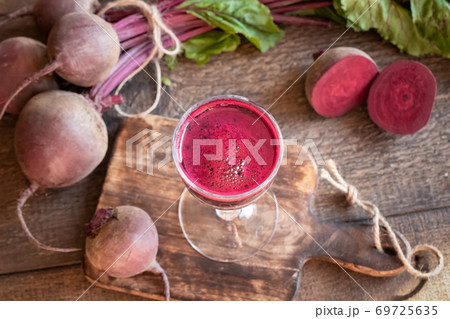 Red beet juice in a glass on a wooden table 69725635