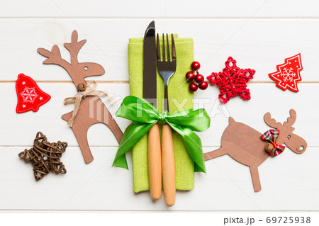 Top view of new year utensils on napkin with holiday decorations and reindeer on wooden background. Christmas dinner concept with copy space 69725938