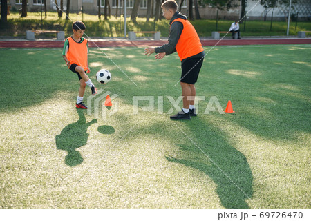 Young soccer coach instructs teen players. A young professional coach trains the ball kicks with young football players. 69726470