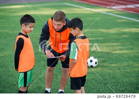 Football coach instruct teen football players. Young professional coach ...