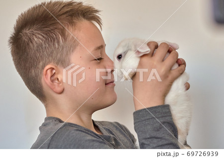 a boy with a white rabbit in his hands 69726939