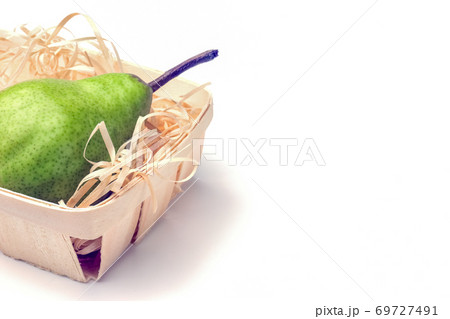 green pear in a basket close-up on a white background 69727491