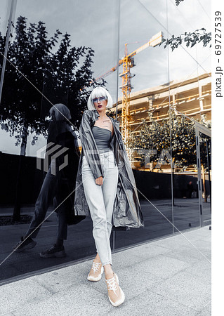 Stylish blonde in futuristic clothes and glasses on a mirror background. Stylish blonde in futuristic clothes and glasses on a mirror background. 69727539