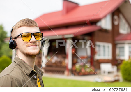 bearded guy in yellow glasses listening to music online through headphones bearded guy in yellow glasses listening to music online through headphones 69727881