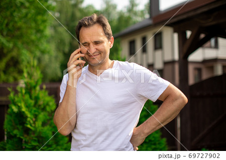 Happy middle aged man talking by smartphone, smiling man standing outdoors 69727902