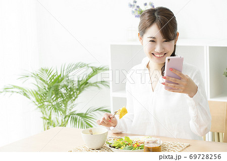食事をしながらスマホを見る女性 食事をしながらスマホを見る女性 69728256
