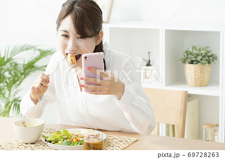 食事をしながらスマホを見る女性 食事をしながらスマホを見る女性 69728263