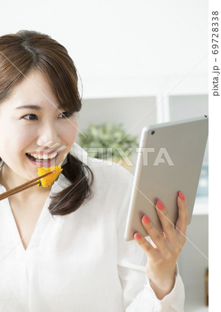 タブレットPCを見ながら食事する女性 タブレットPCを見ながら食事する女性 69728338