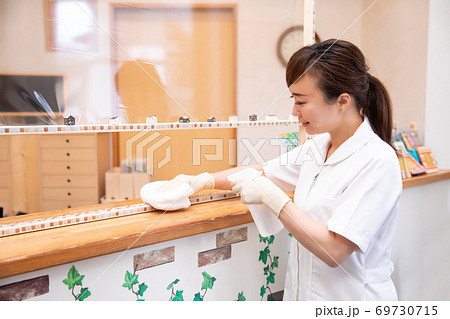 受付カウンターを消毒する医療スタッフ 69730715