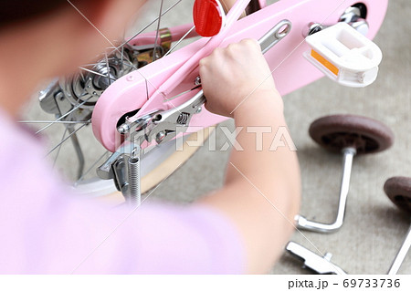 自転車の補助輪とスタンドを取り外しする女性 69733736