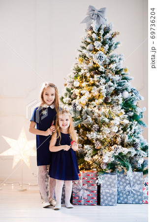 girls in blue on background of Christmas tree. 69736204
