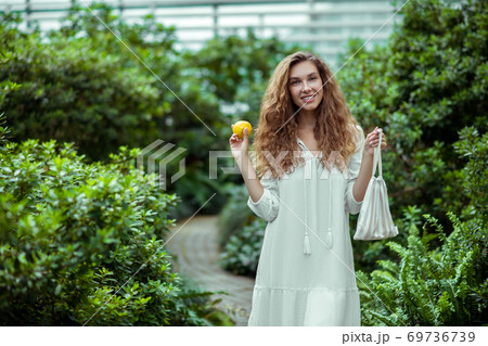 Cute woman in white dress holding a lemon and smiling 69736739