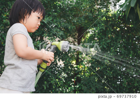 Funny moment of 3 Year old asian kid playing water with garden hose in backyard. Background concept for play time and summer of children. Funny moment of 3 Year old asian kid playing water with garden hose in backyard. Background concept for play time and summer of children. 69737910