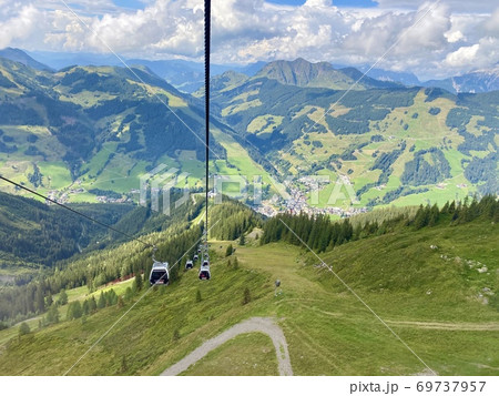 Aerial view on Saalbach village and mountains in Saalbach-Hinterglemm skiing region in Austria on a beautiful summer day from cableway on the village with holiday ressorts, the church and other Aerial view on Saalbach village and mountains in Saalbach-Hinterglemm skiing region in Austria on a beautiful summer day from cableway on the village with holiday ressorts, the church and other 69737957