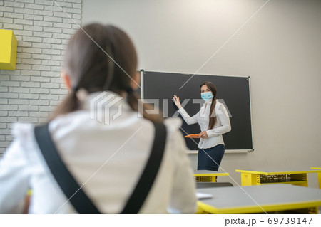 Schoolgirl sitting at the desk and listening to her teacher Schoolgirl sitting at the desk and listening to her teacher 69739147