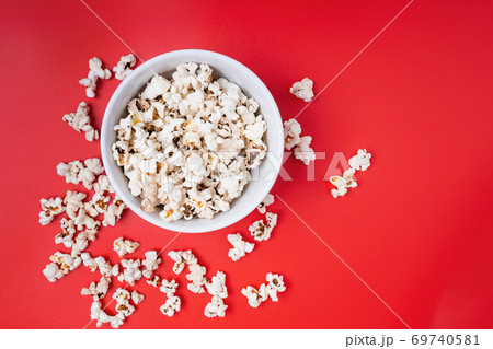 Bowl of popcorn and controller on red background Bowl of popcorn and controller on red background 69740581