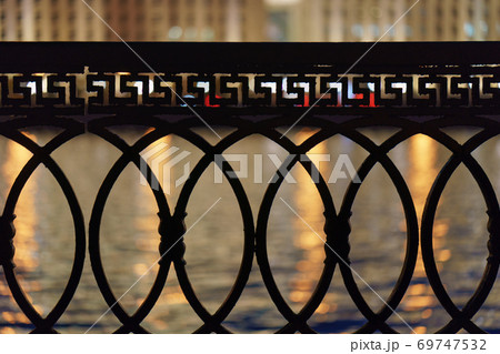 View of Moskva river, city reflections at the water through the metal fence. Concept of the beauty of the Moscow city in night. Buildings across the river. View of Moskva river, city reflections at the water through the metal fence. Concept of the beauty of the Moscow city in night. Buildings across the river. 69747532