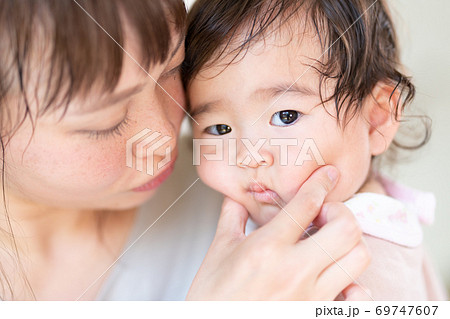 赤ちゃんのほっぺたをぷにぷにする若いお母さんの写真素材
