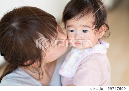 お母さんにほっぺたにキスをされる赤ちゃんの写真素材