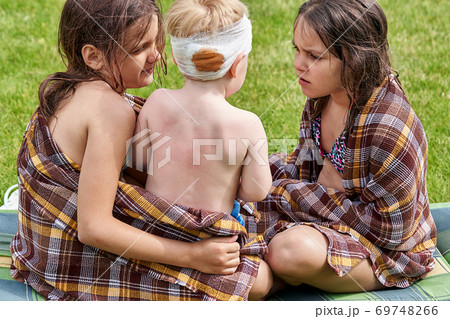 Two teenage girls feel sorry for little brother with bandaged head Two teenage girls feel sorry for little brother with bandaged head 69748266