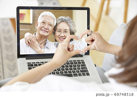 asian adult daughter forming a heart shape with hands while talking to senior parents via video chat asian adult daughter forming a heart shape with hands while talking to senior parents via video chat 69748518