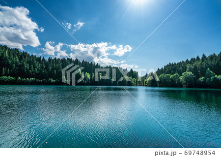 Beautiful view of a lake with white pluffy cloudy sky and mountain background. Travel Tourism concept. Beautiful view of a lake with white pluffy cloudy sky and mountain background. Travel Tourism concept. 69748954