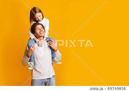 Happy father carrying his cheerful little daughter on shoulders 69749856