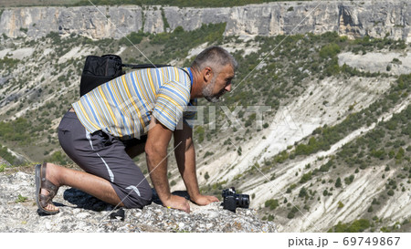 An adult man on the edge of the gorge, side view, is on all fours. Man over the gorge. 69749867