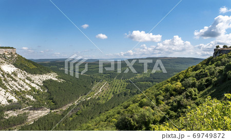 Landscape of a green plain in a mountainous gorge. White slopes of steep mountains. Landscape of a green plain in a mountainous gorge. White slopes of steep mountains. 69749872