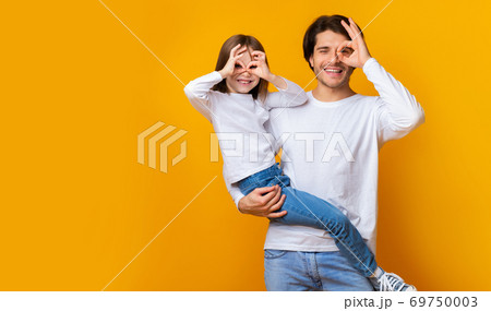 Joyful dad and daughter having good time over yellow background 69750003
