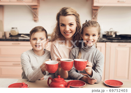 Mom and children are sitting at a table. 69752403