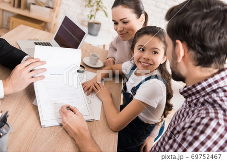 Man with wife and daughter signs sales contract. 69752467