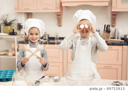 Boy is holding eggs and sister is holding spoons. Boy is holding eggs and sister is holding spoons. 69752613