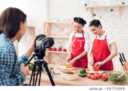 Two happy culinary bloggers dicing peppers. Two happy culinary bloggers dicing peppers. 69753069