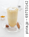a glass of curcuma latte with glass tube on white table closeup 69753142