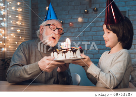 Grandson holds cake for grandfather.  69753207
