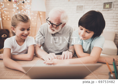 Grandfather with grandchildren sitting at laptop. 69753482
