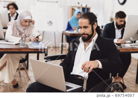 Disabled arab man in wheelchair working in office. Disabled arab man in wheelchair working in office. 69754007