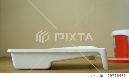 Close-up plot of pouring a viscous light substance from a can. Pouring acrylic paint into white plastic tray to make improvement on floor. 69756476