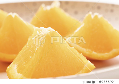Freshly sliced oranges on a dotted brown plate. Macro with selective focus. 69756921