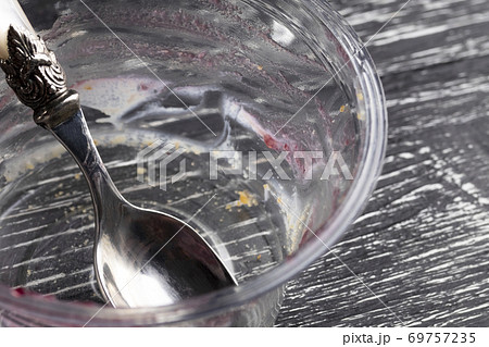 empty plastic packaging with a spoon, leftovers eaten by teramis on a dark wooden background empty plastic packaging with a spoon, leftovers eaten by teramis on a dark wooden background 69757235