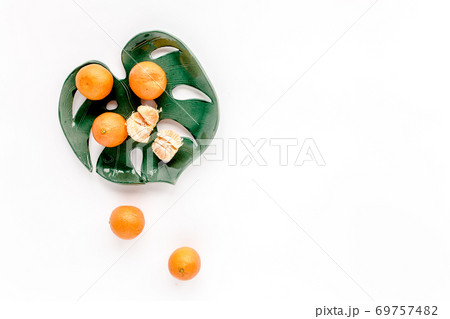 Ceramic plate-leaf Monstera with tangerines isolated on white background. Flat lay, top view.  69757482